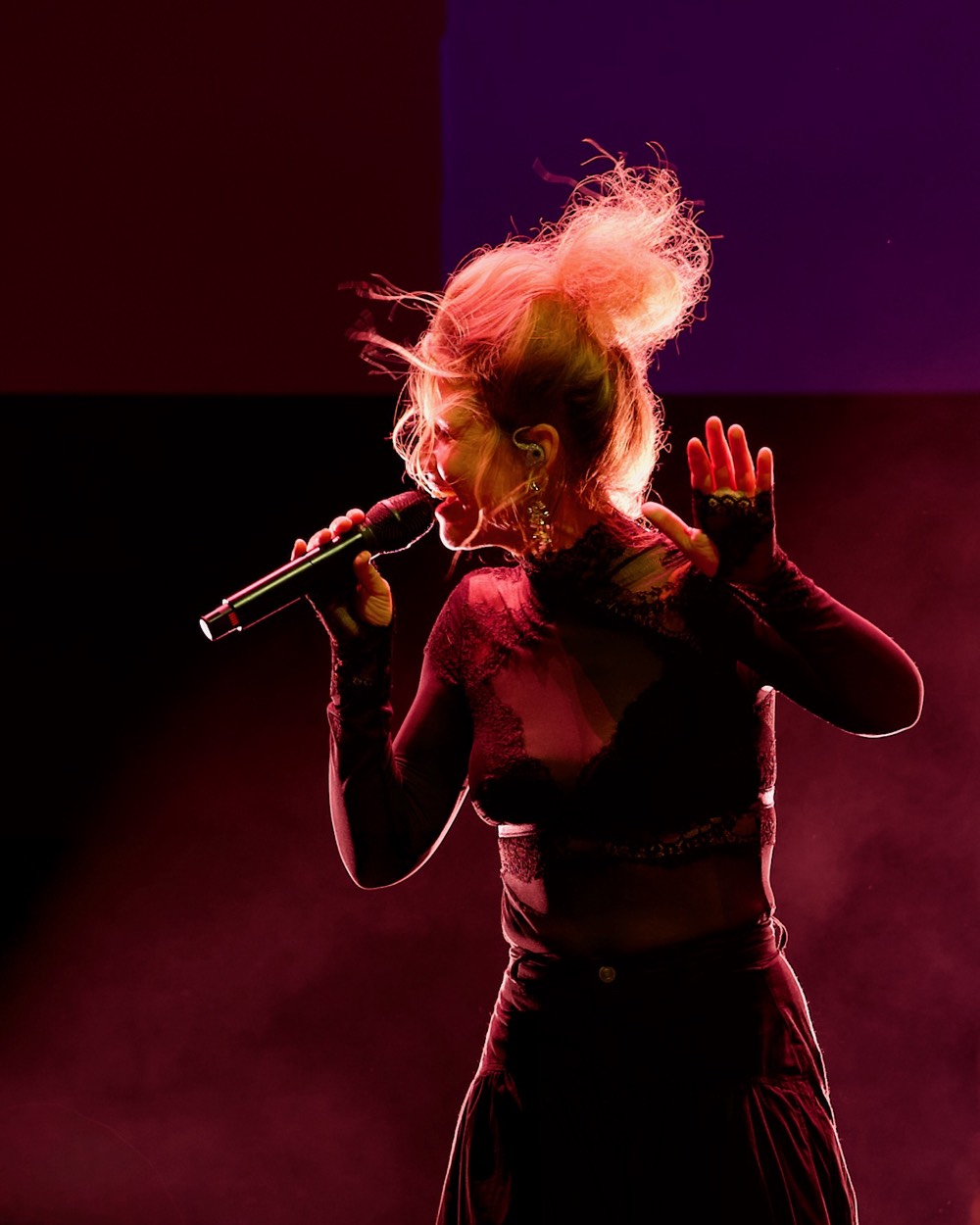 Chanteuse blonde au micro dans une lumière rouge